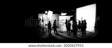 Silhouette images of film production. behind the scenes or b-roll of making video commercial movie. Film crew lightman and cameraman working together with film director in studio. Film industry. Royalty-Free Stock Photo #2020627955