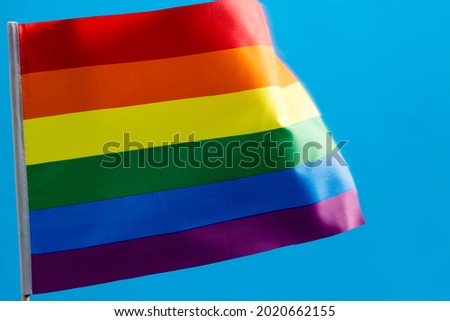 Rainbow flag waving on blue background.