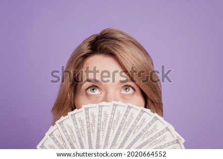 Photo of young pretty woman closing face bunch of dollars look up wealthy isolated over violet color background