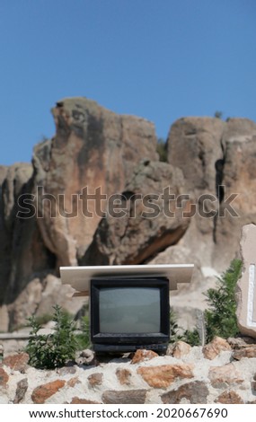Antique television is in front of the rocks 