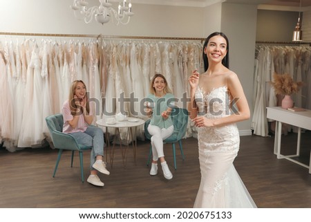 Bride with friends choosing wedding dress in boutique
