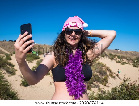 Brunette girl in sunglasses making selfie in weekend at summer resort. Outdoor shot of young lady taking picture of herself while new year celebrations at ocean beach. copy space