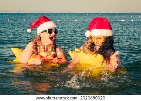 A picture of a group of women in bikini and Santa hats floating on an inflatable mattress. Christmas celebrations at resort concept