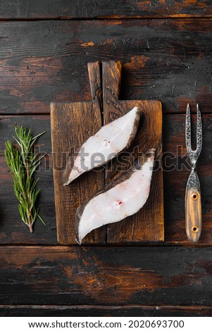 Raw halibut saltwater fish steak set, with ingredients and rosemary herbs, on old dark  wooden table background, top view flat lay