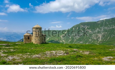 A small stone mosque against the backdrop of picturesque green mountains. Republic of Dagestan, Russia Royalty-Free Stock Photo #2020695800