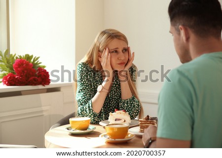 Young woman getting bored during first date with man in cafe Royalty-Free Stock Photo #2020700357