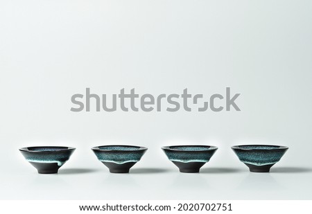 Green tea in a dark turquoise small clay cups lined on pastel background. Creative minimalist tea ceremony concept. Copy space.