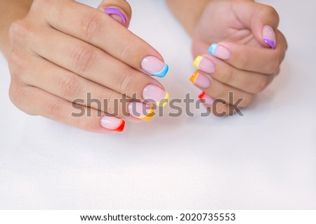 Hands of a young woman with a manicure. The nails are covered with gel polish with colored French. Royalty-Free Stock Photo #2020735553