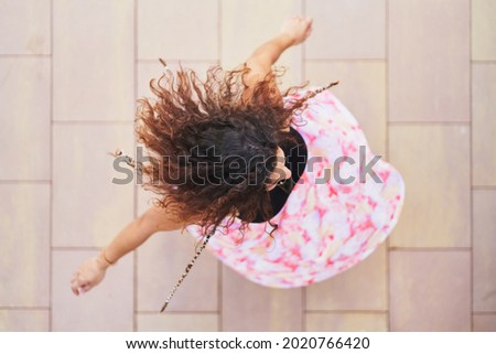 Top view of unrecognizable woman spinning and dancing on street