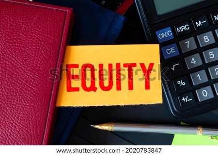 word equity written on a yellow and white background near a computer keyboard and calculator. High quality photo