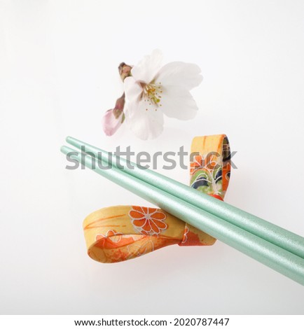 Wooden chopsticks and chopstick rest on bright paper background. 