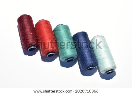 Close up of red, orange, light green, navy blue and white sewing thread isolated on a white background. Hand made things


