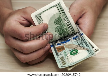 a man counts hundred-dollar bills sitting at a table. High quality photo