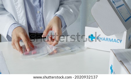 Close-up hand asia woman chemist help pack covid free first aid self recover care on desk give for customer people buy online clinic retail Rx drug store in telehealth telemedicine e-commerce order. Royalty-Free Stock Photo #2020932137