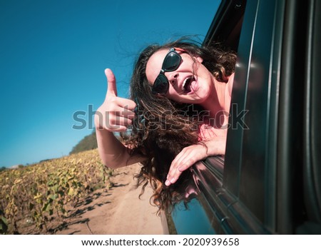 happy teenage girl or young woman in car at sea - summer vacation, vacation, travel, road trip and people concept. Ok gesture