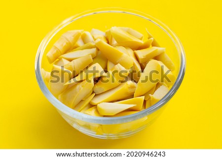 Preserved bamboo shoot in glass bowl on yellow background.