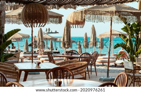 Beach  club view, modern white sun beds, knitted makrome umbrellas for sun protection, sea on background, food corner tables Royalty-Free Stock Photo #2020976261