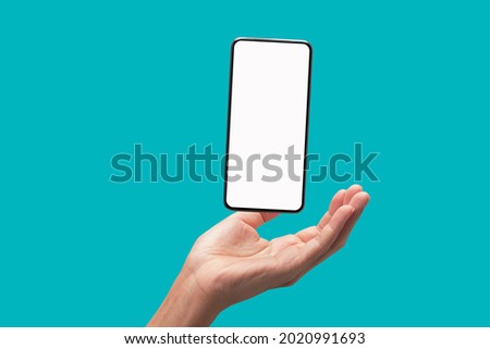 The palm of the hand supports the floating smart phone, isolate on blue green background Royalty-Free Stock Photo #2020991693