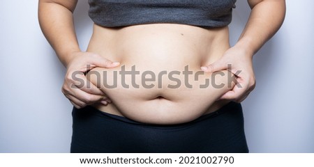 Fat woman hand holding fat belly on white background. Royalty-Free Stock Photo #2021002790