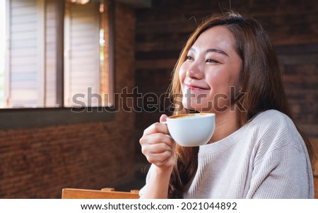 Portrait image of a beautiful young asian woman holding and drinking coffee