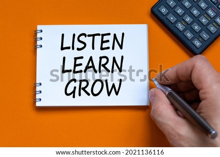 Listen, learn, grow symbol. Businessman writing words Listen, learn, grow on white note. Black calculator. Beautiful orange background. Business, educational, listen, learn, grow concept. Copy space.