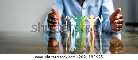 Inclusion, Diversity And Equality. African Hands Safeguard Paper Shapes Royalty-Free Stock Photo #2021185625