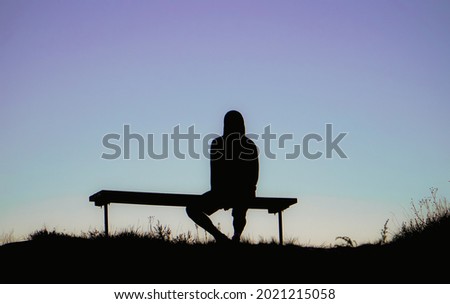 guy seated in a bench looking the sunset