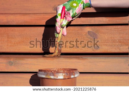painting of terrace boards with impregnation, varnish or wax to protect wood, repair and renovation of housing Royalty-Free Stock Photo #2021225876