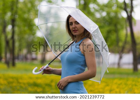 Young woman with transparent umbrella on blurred background of city park. Copy space for text