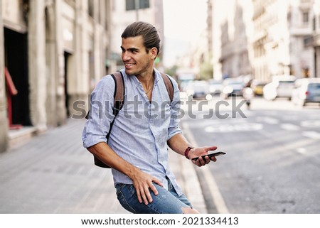 young handsome man smiling with smartphone at via laietana in Barcelona