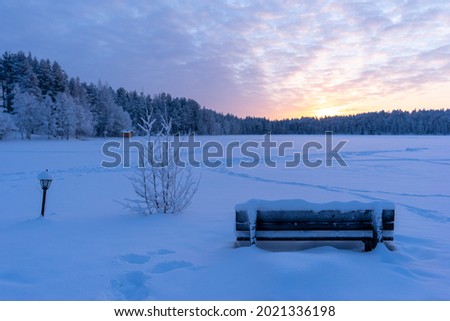 Bench in front of frozen lake during Winter
