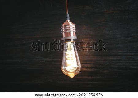 Vintage modern light bulb over wooden background.