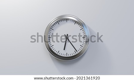 Glossy chrome clock on a white wall at twenty-four past six. Time is 06:24 or 18:24 Royalty-Free Stock Photo #2021361920