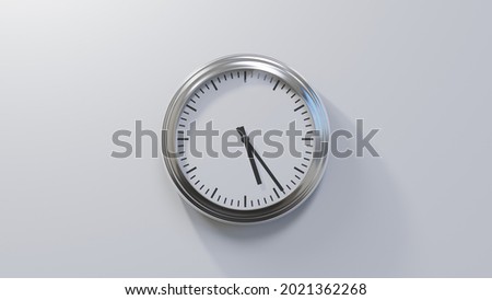 Glossy chrome clock on a white wall at twenty-four past five. Time is 05:24 or 17:24 Royalty-Free Stock Photo #2021362268