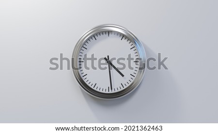 Glossy chrome clock on a white wall at twenty-nine past four. Time is 04:29 or 16:29 Royalty-Free Stock Photo #2021362463
