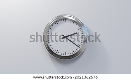 Glossy chrome clock on a white wall at twenty-one past two. Time is 02:21 or 14:21