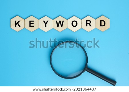 Keyword on hexagon wooden plate with magnifying glass. Search keyword concept