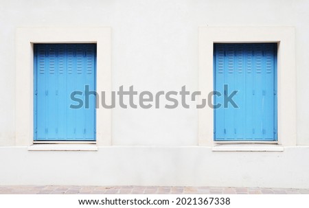 Real two blue window on white grung wall with brick foot path, street photo background.