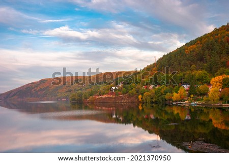 mountain lake somesul cald at sunset. beautiful autumnal countryside landscape of cluj country, romania. trees on the hill in colorful foliage and clouds on the sky reflecting on the water surface
