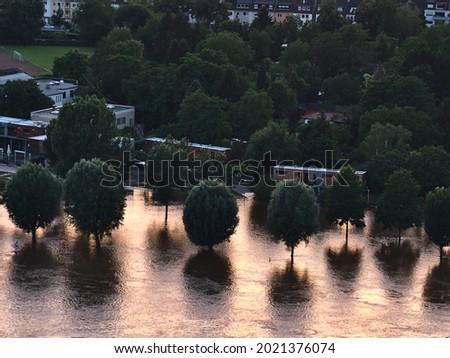 Aerial view of flooded riverbank of Rhine river in Koblenz, Rhineland-Palatinate, Germany at high water level with houses and trees reflected in the water in the evening light. Royalty-Free Stock Photo #2021376074