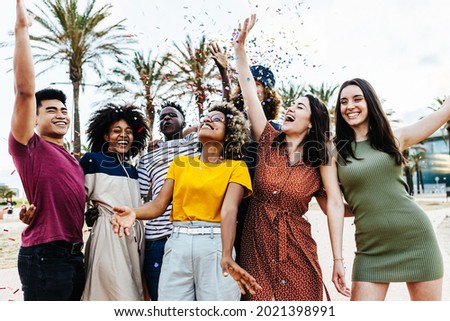 Young multiracial hipster people having fun in summer party celebration - Group of young friends laughing and celebrating all together while throwing coloured confetti at weekend event outdoors Royalty-Free Stock Photo #2021398991