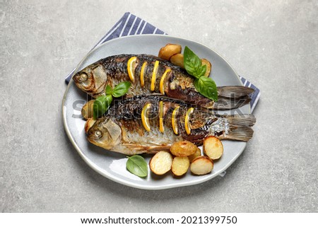 Tasty homemade roasted crucian carps with garnish on light grey table, top view. River fish Royalty-Free Stock Photo #2021399750