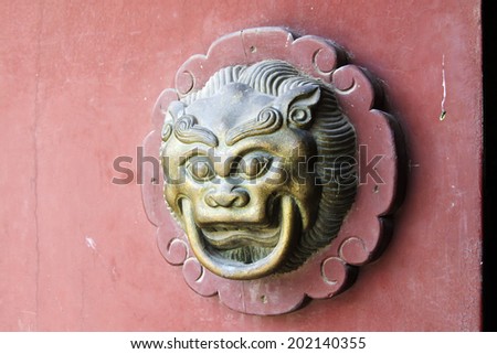 beast sculpture on red wooden door in a temple, closeup of photo