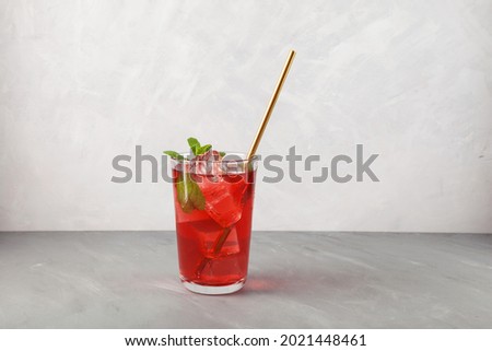 Red refreshing drink with mint on grey background. Colorful summer non-alcoholic refreshing drink with ice, fruit iced tea. Royalty-Free Stock Photo #2021448461