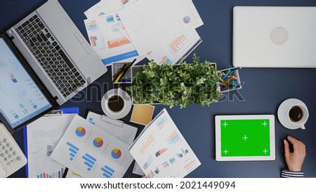 Top view of businesswoman looking at mock up green screen chroma key tablet with isolated display while drinking coffee in startup company office. Manager brainstorming management accounting ideas