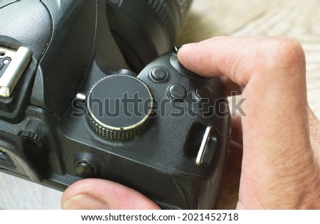 finger pushing shutter button of digital single lens reflect camera on table