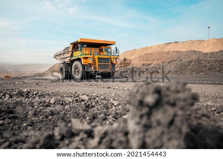 Large quarry dump truck. Big yellow mining truck at work site. Loading coal into body truck. Production useful minerals. Mining truck mining machinery to transport coal from open-pit production Royalty-Free Stock Photo #2021454443