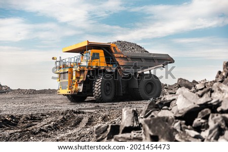 Large quarry dump truck. Big yellow mining truck at work site. Loading coal into body truck. Production useful minerals. Mining truck mining machinery to transport coal from open-pit production Royalty-Free Stock Photo #2021454473