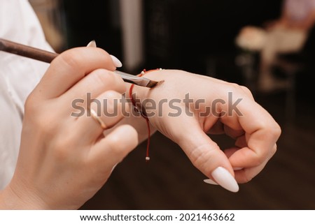 Shooting in a beauty salon. A picture of the hands of a makeup artist who is typing a cosmetic product with a brush.
