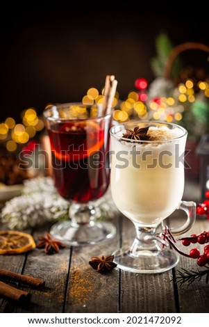 fresh yellow eggnog and fruity red mulled wine with Christmas decoration. Selection of autumn or winter alcoholic hot drinks